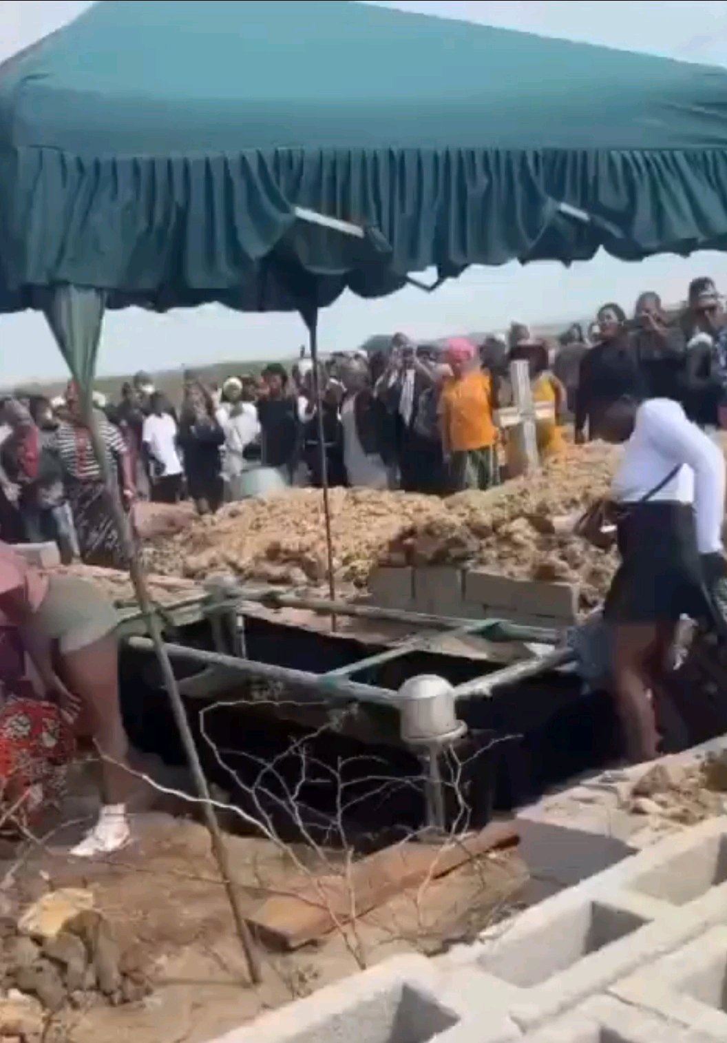 Two women filmed dancing beside an open grave moments after a burial