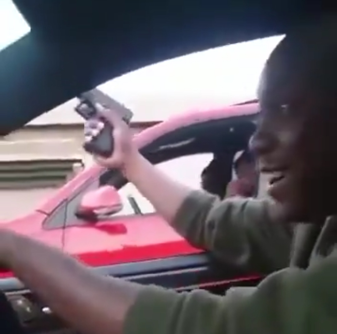 Man filmed holding a gun out towards a red vehicle while driving