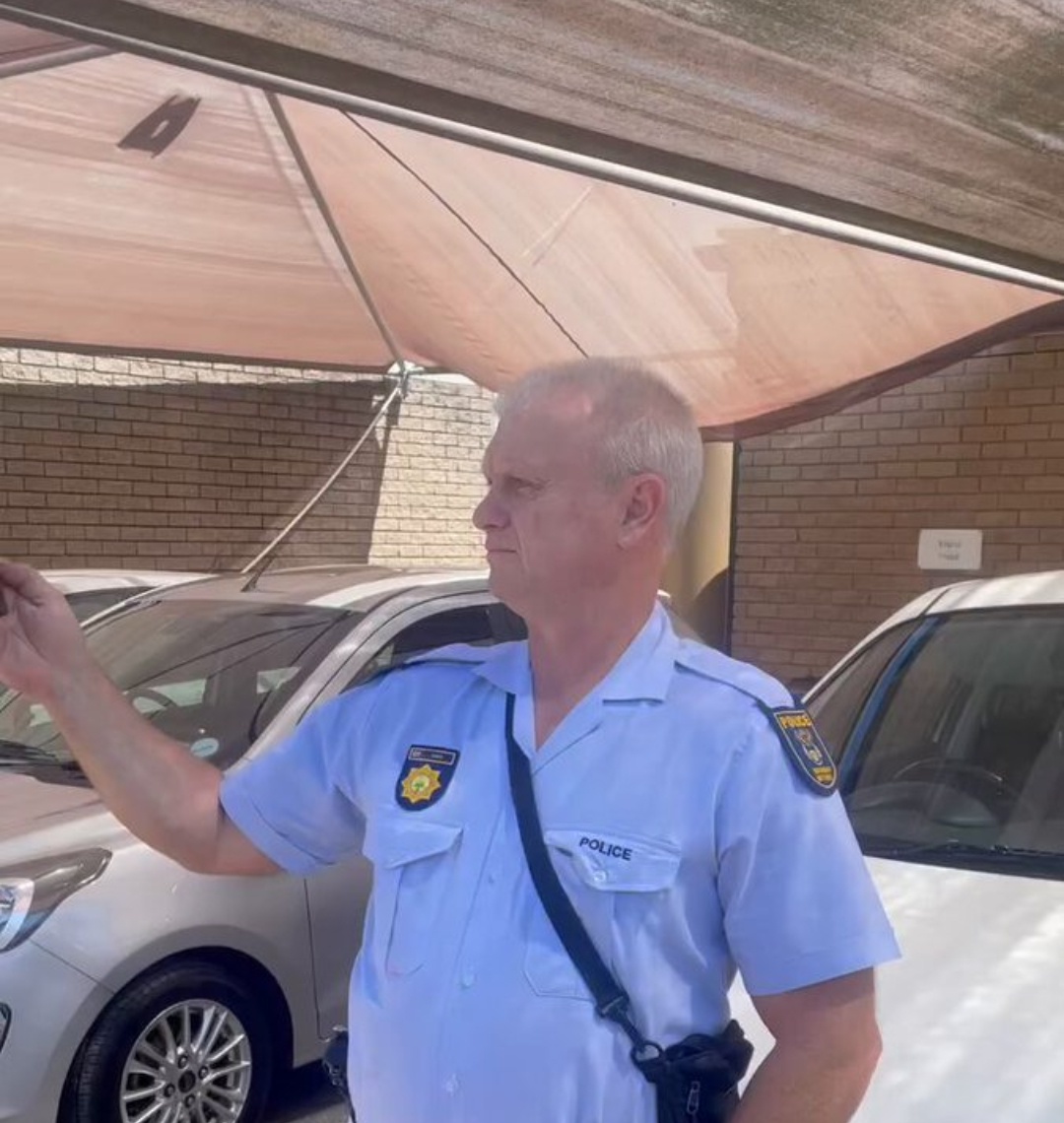 Nigerian men speak respectfully to a white officer at a Parklands police station