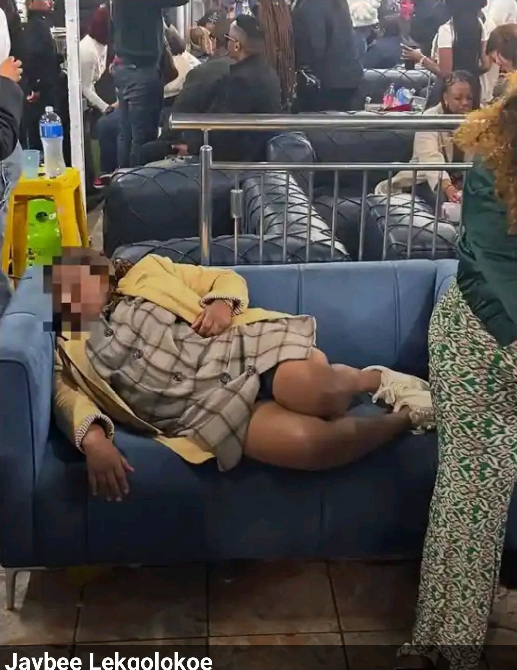 Woman appears intoxicated and asleep on a couch at a busy social venue