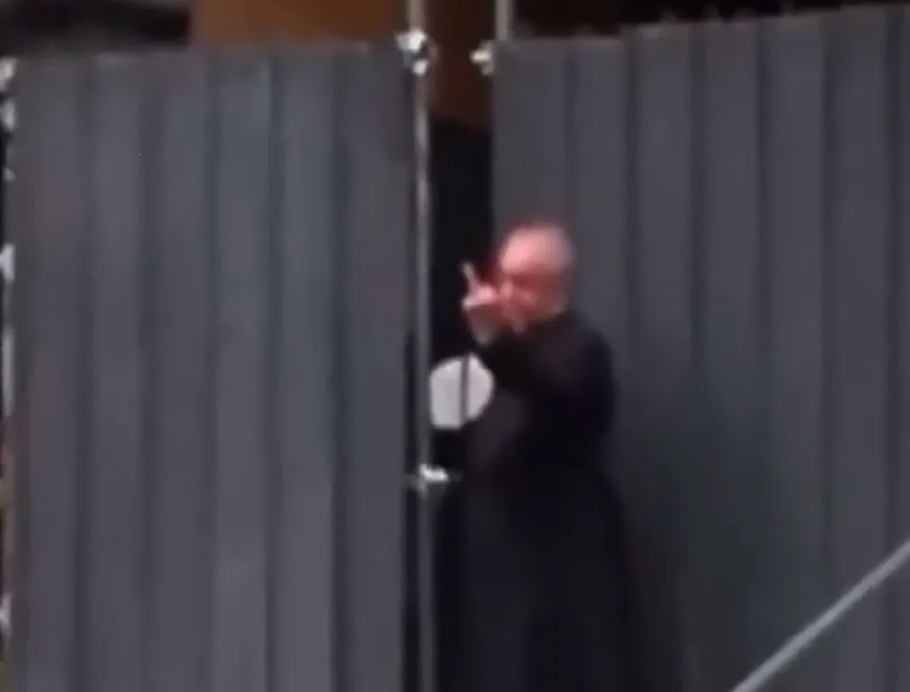 Italian priest gives protesters the middle finger while protecting his congregation from rioters