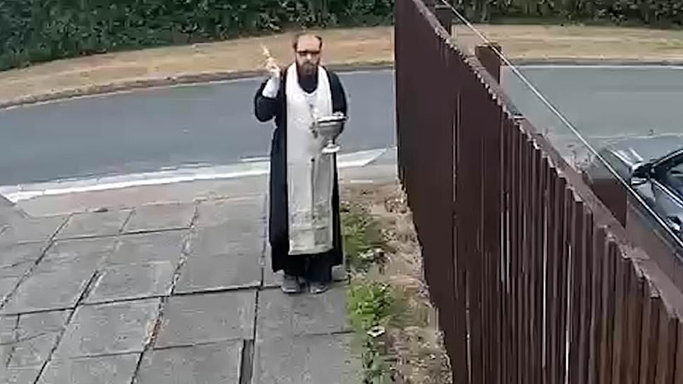 Priest sprinkles holy water over fence during war with neighbour
