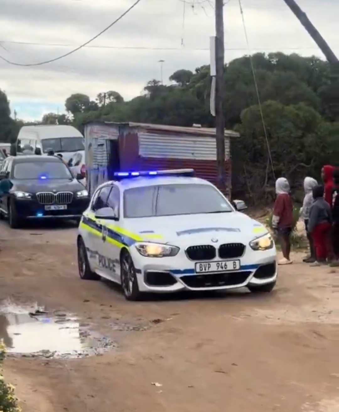 Luxury car convoy with police escort drives past shacks and draws criticism