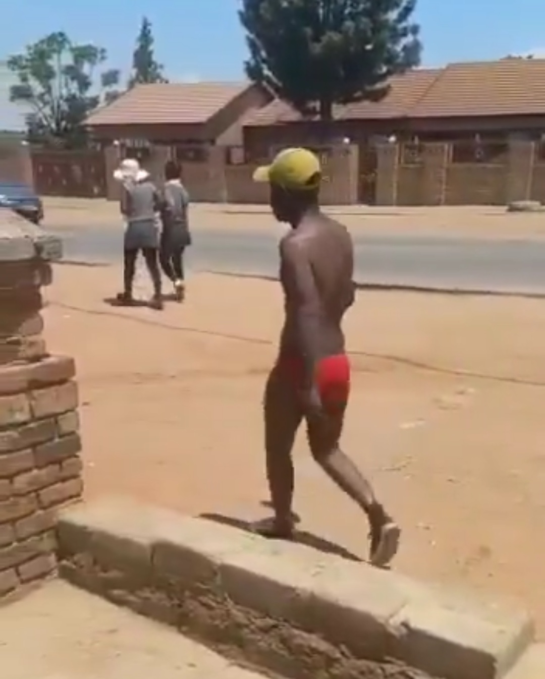 Man in red underwear walks through a township during the day