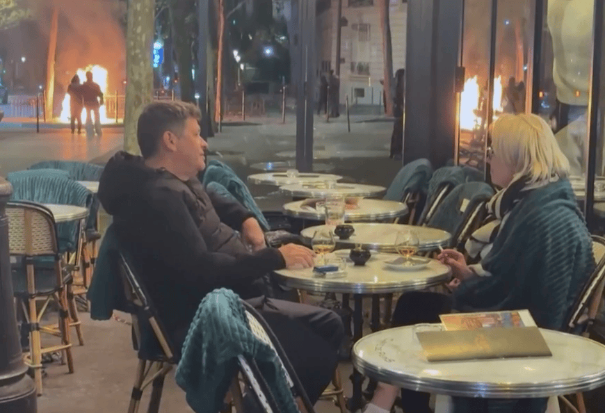 Couple enjoy a drink and a smoke as Paris burns around them